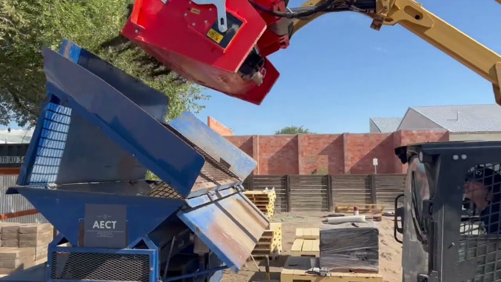 Using a skid-steer mixing attachment to mix compressed earth block material.